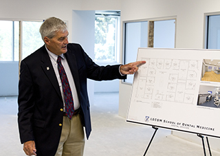 Robert Hirsch, DDS, standing in front of white board presentation in classroom.