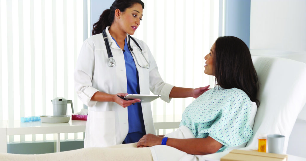 Female Doctor checking on female patient in recovery room