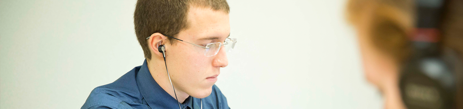 Male student with headphones on tablet studying at LECOM in Erie, PA