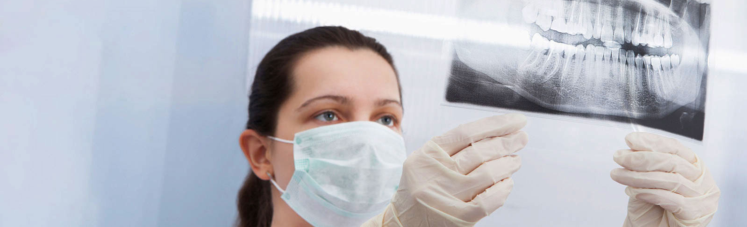 Woman in mask and gloves looking at dental xray by LECOM