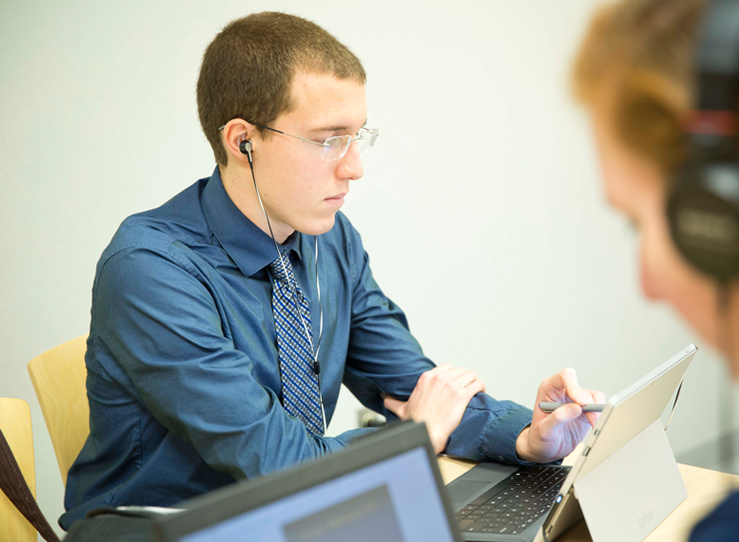 Male student with headphones looking at tablet at LECOM