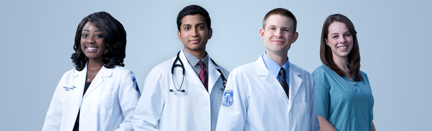 One black female student in white coat, two male students in LECOM white coats, and one female student in blue scrubs