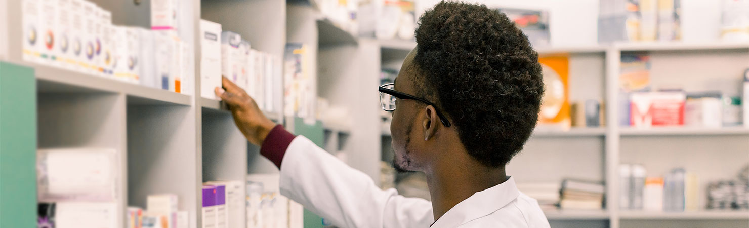 Confident African American man pharmacist standing in interior of pharmacy