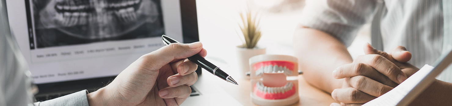 Two peoples hands on desk with dentures